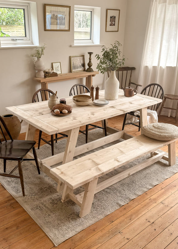 Refectory Rustic Dining Table - Light solid wood table with bench in a dining room setting, with white walls and decor.