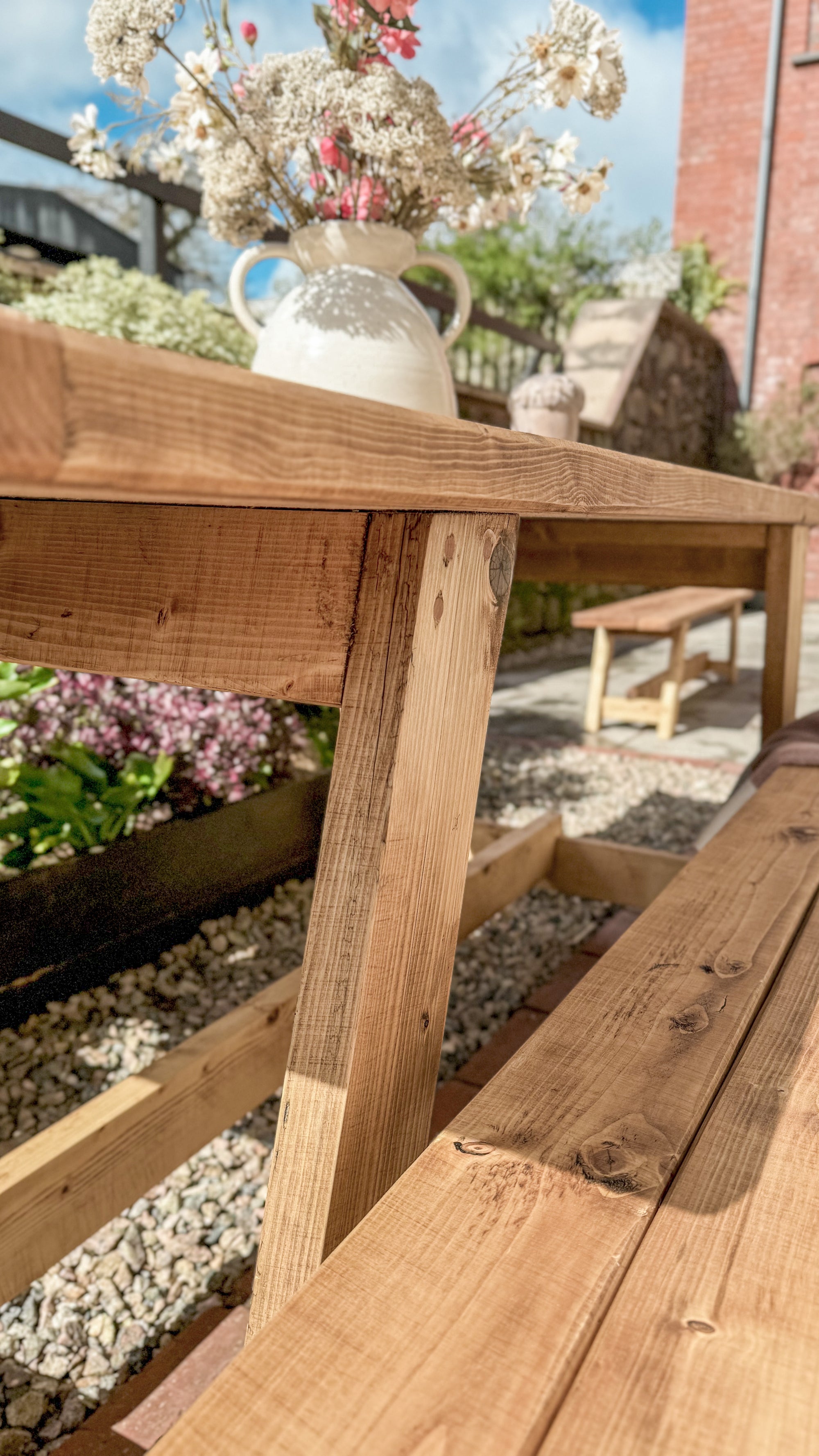Wooden outdoor table with a vase of flowers on a patio