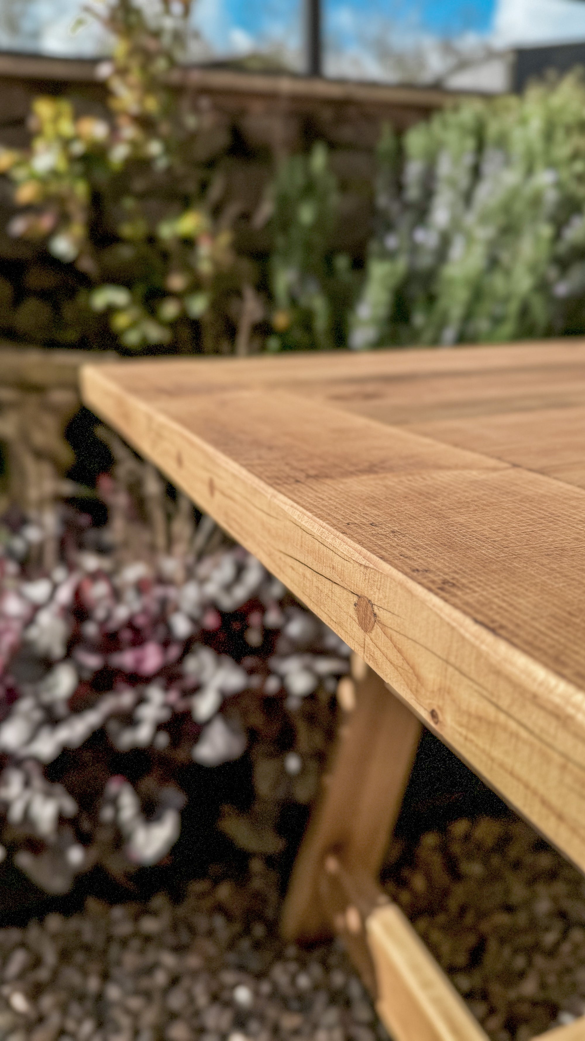Wooden garden table top with a blurred garden background