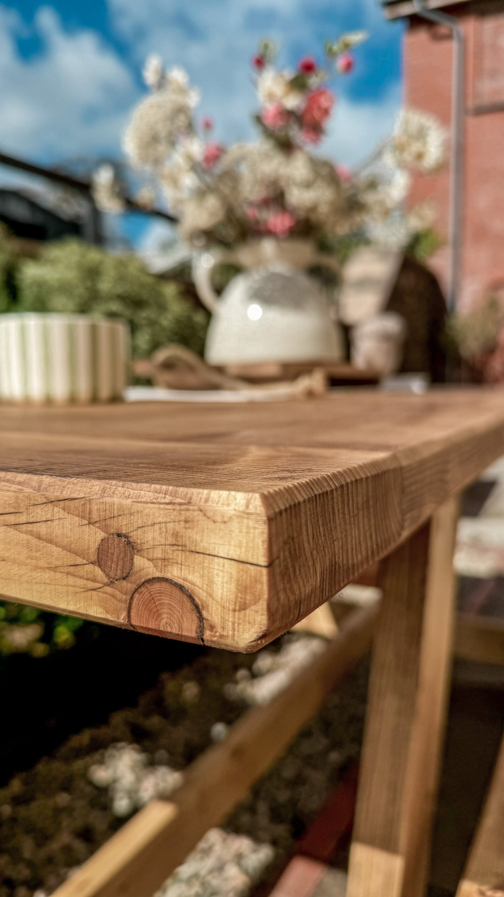 Wooden outdoor table with a blurred background of flowers and outdoor setting