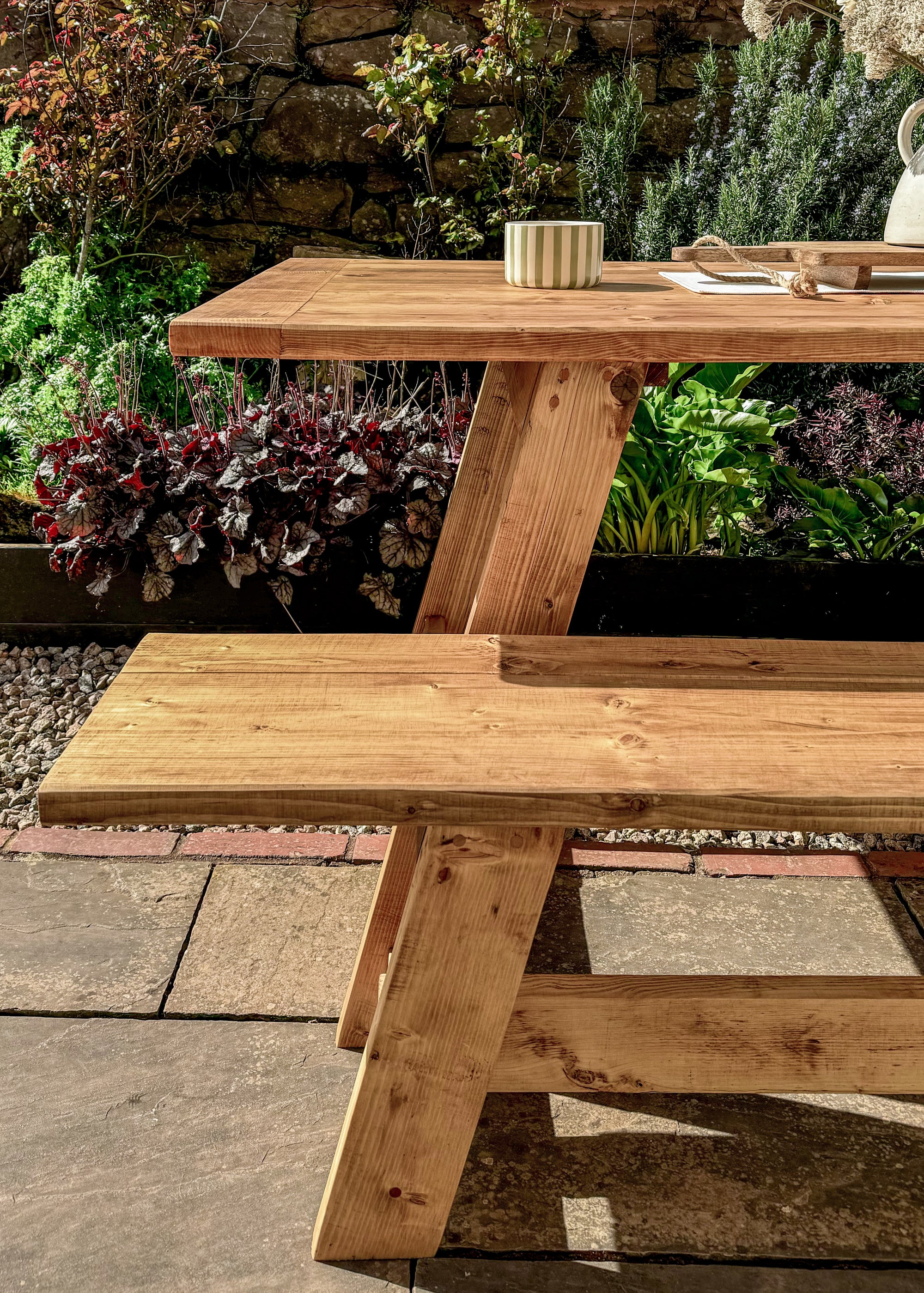 Wooden picnic table with benches in a garden setting