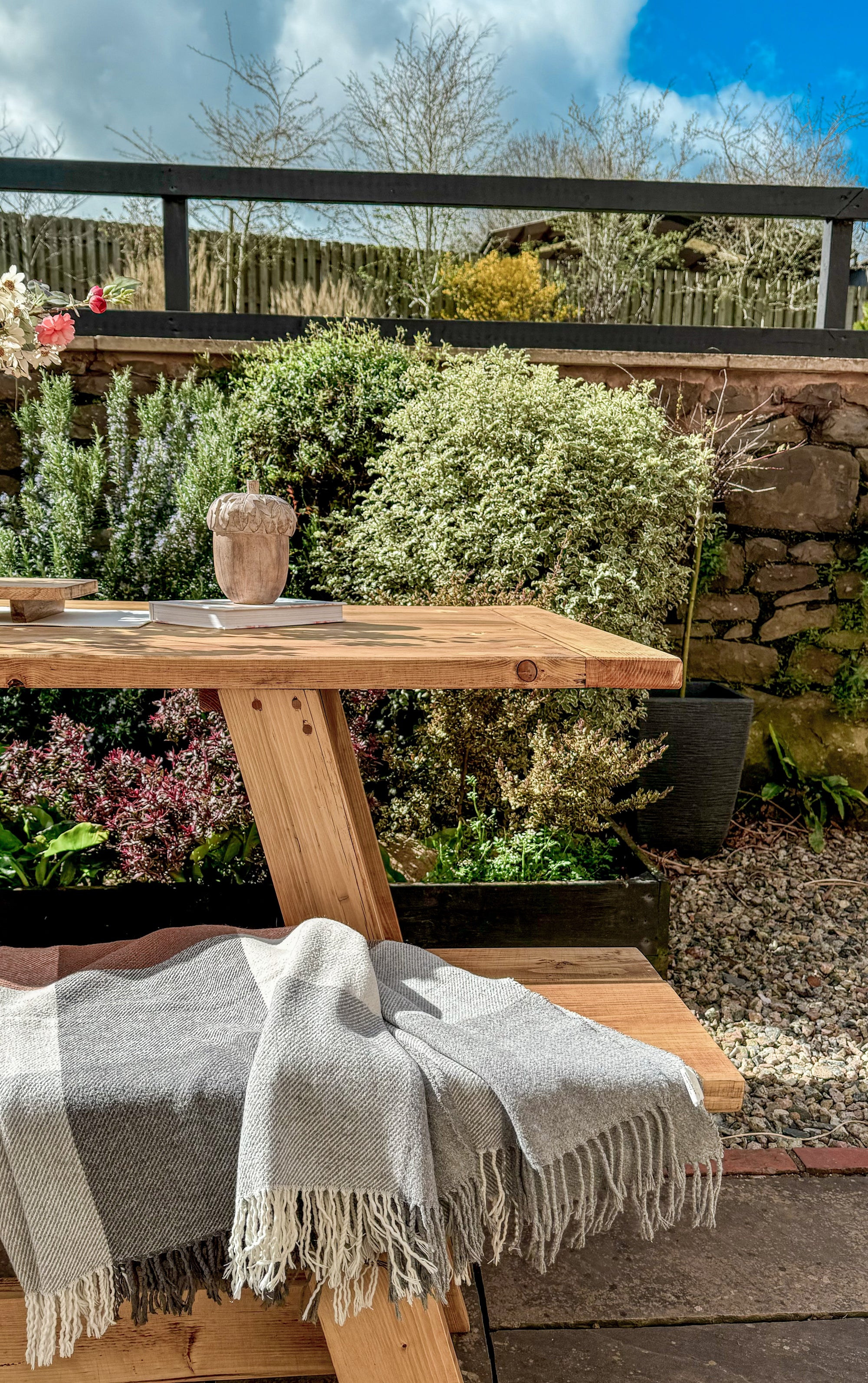 Wooden garden table with a gray blanket in a garden setting
