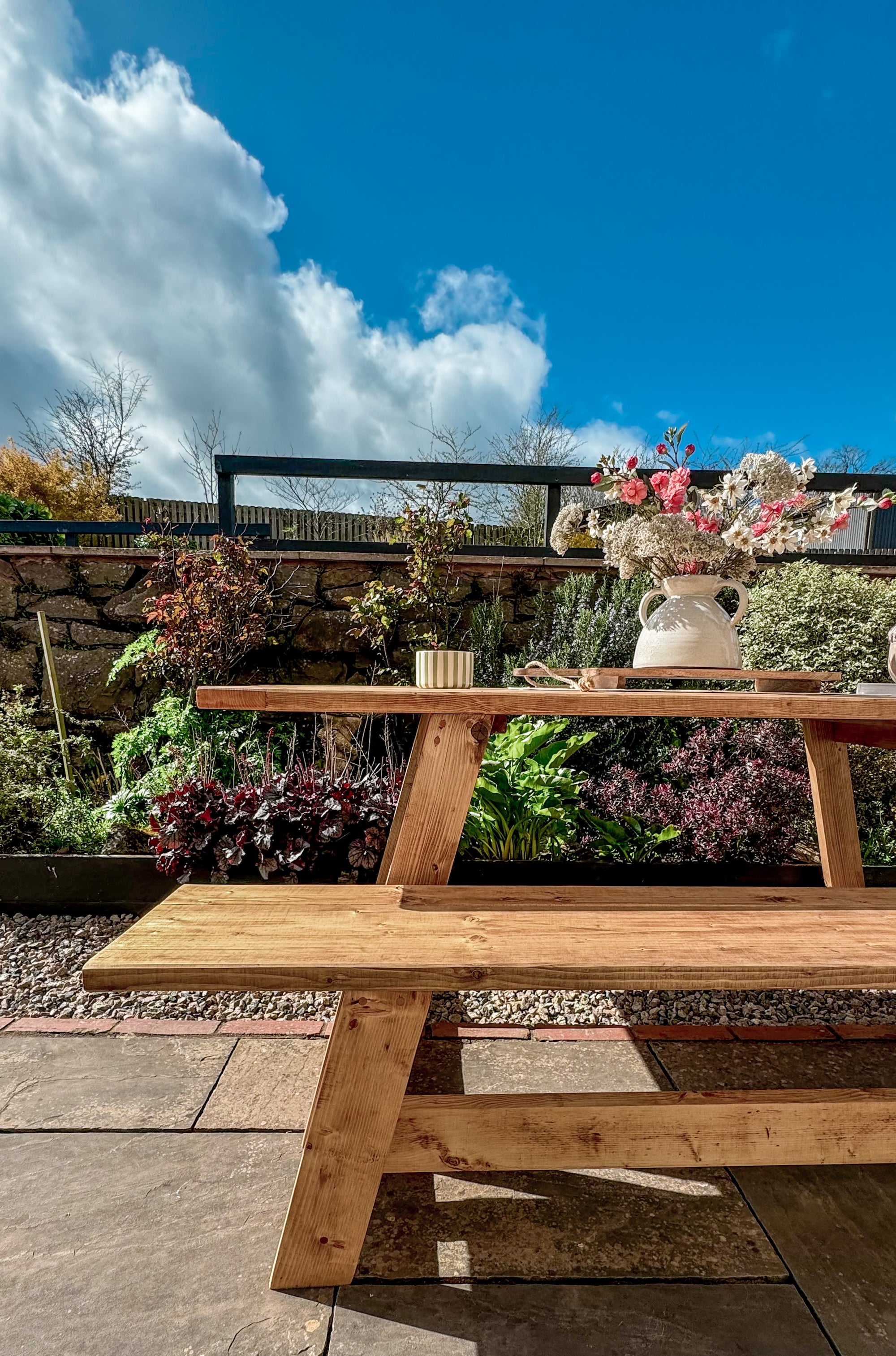 Wooden picnic table with flowers in a garden setting