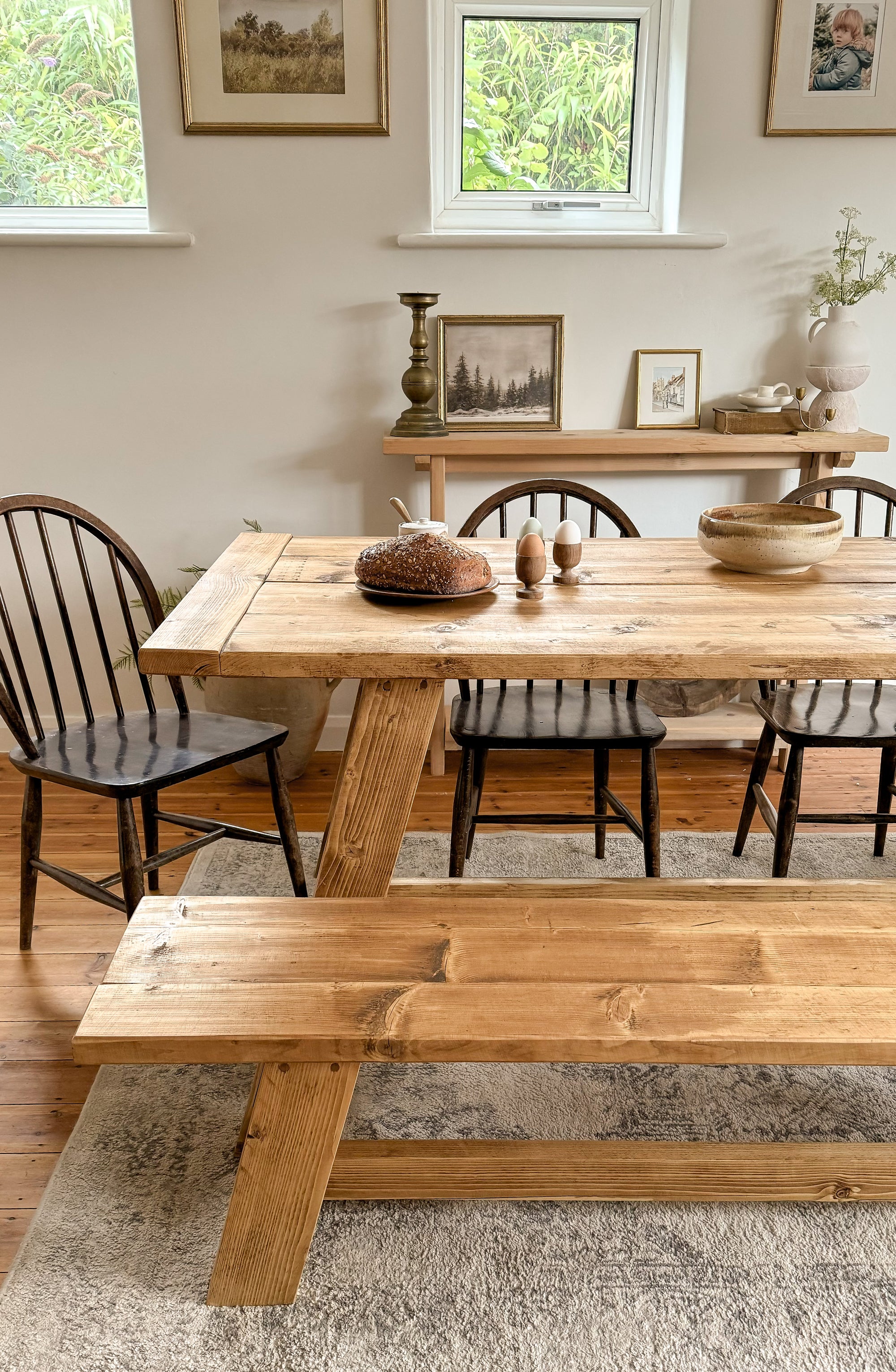 Close up of the end of the farmhouse dining table with bench, showing how to style with chairs and a narrow console table.