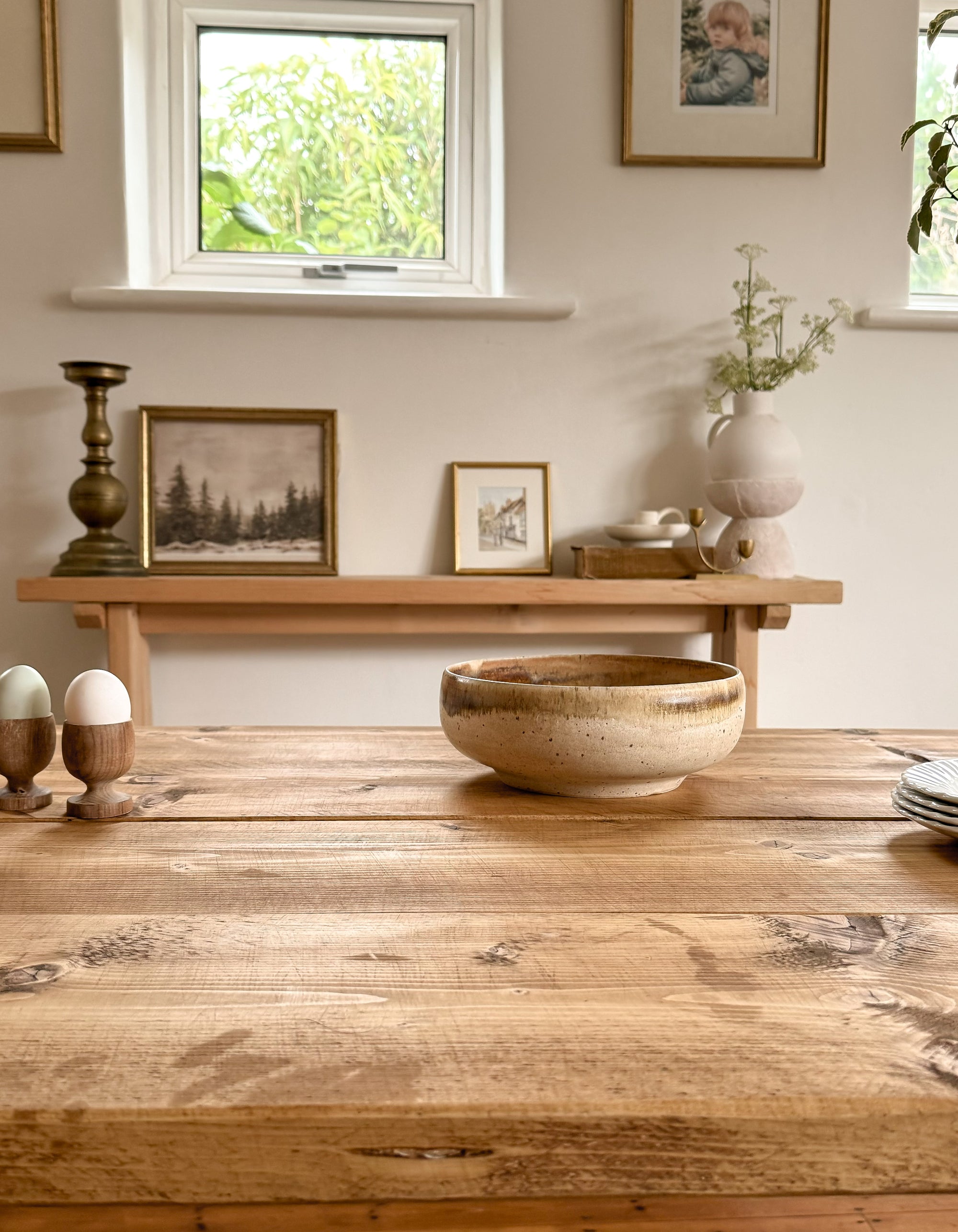 A side on view of the rustic dining table top, showing the antique oak finish and a bowl and eggs ontop of the wood.