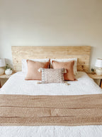A wooden headboard in a bedroom. The wood is rustic and reclaimed
