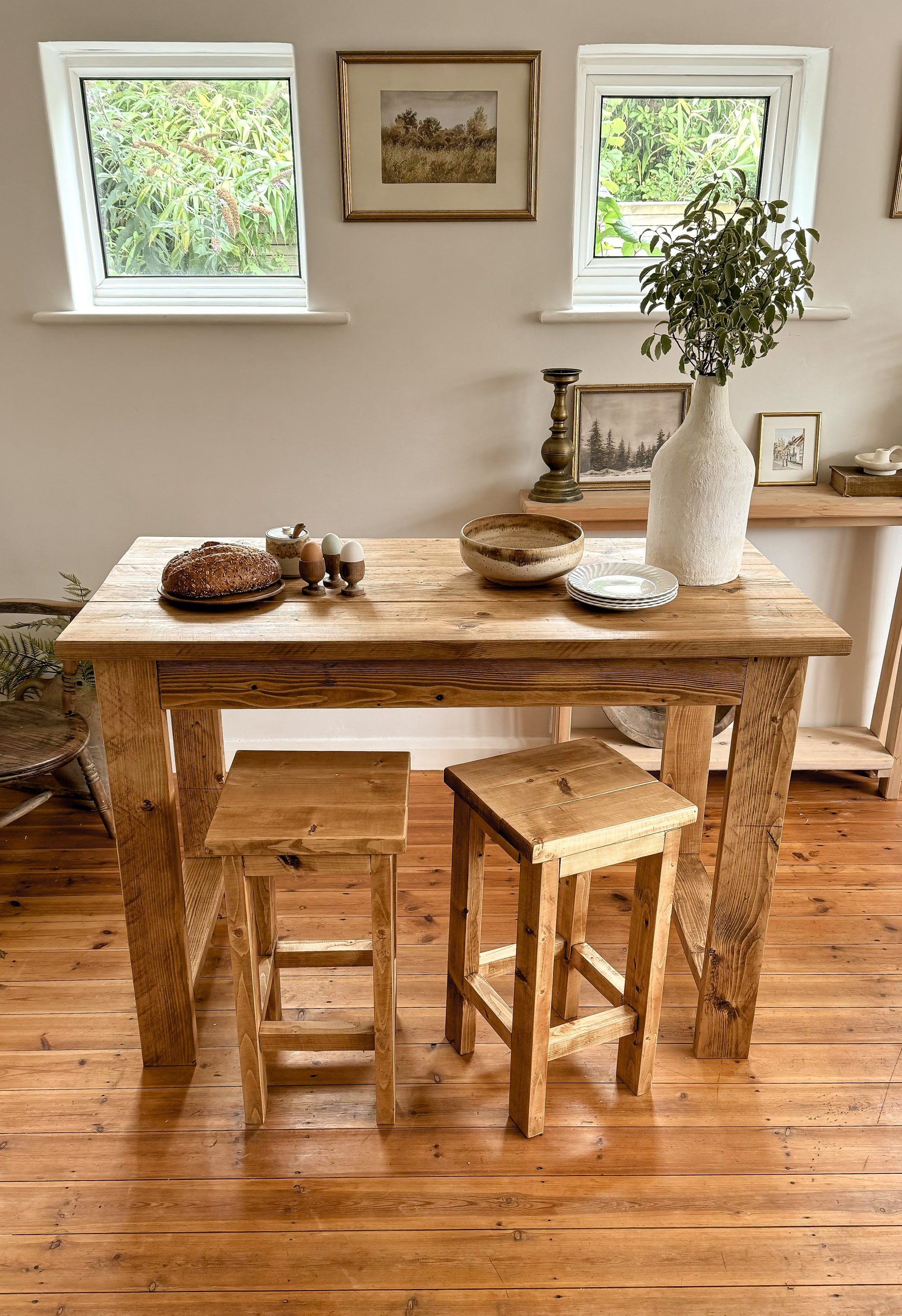 bar table with stools in a room with windows and decor.