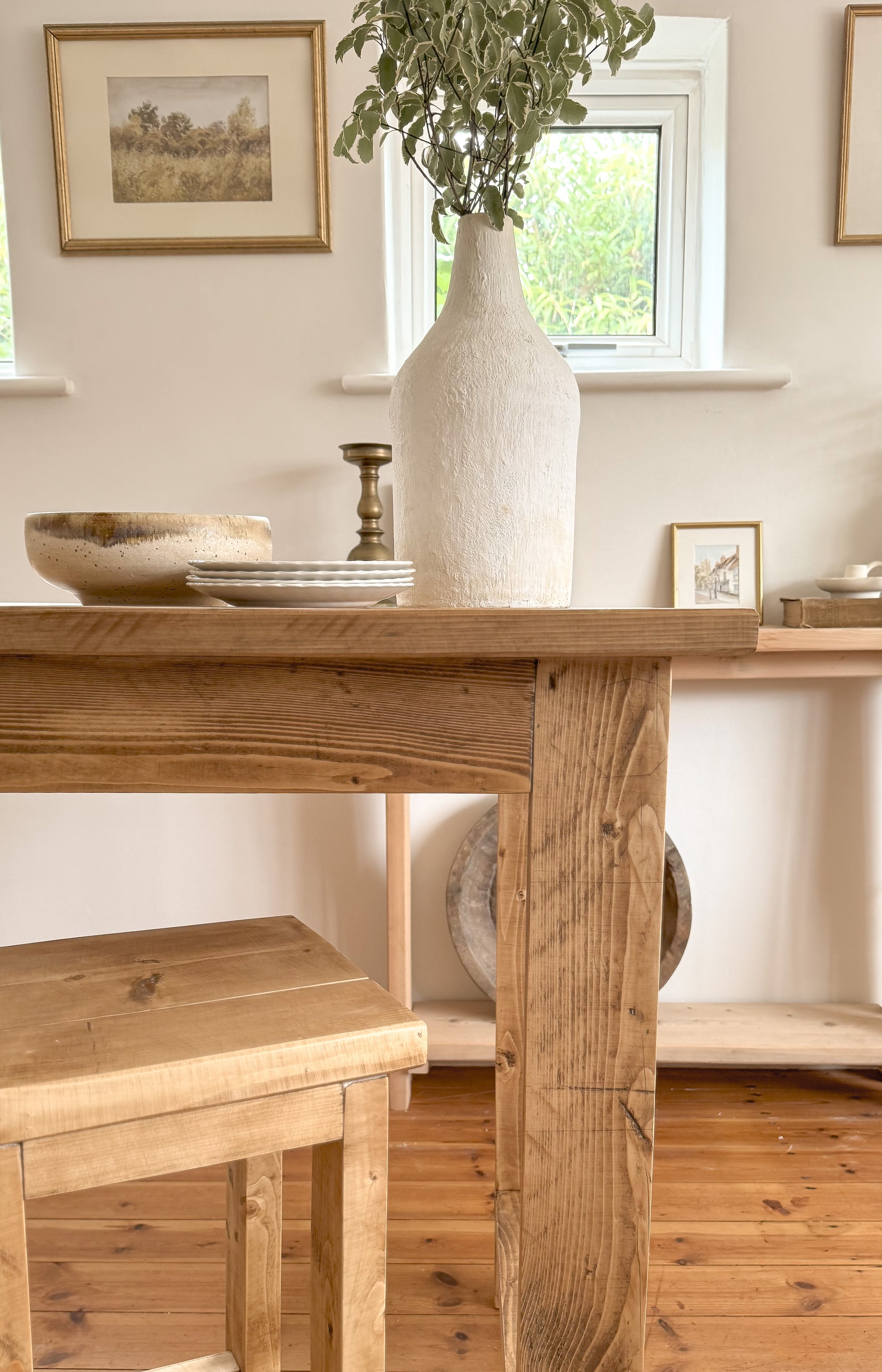 Kitchen bar table with a vase and decor items in a room with a window and wall art.