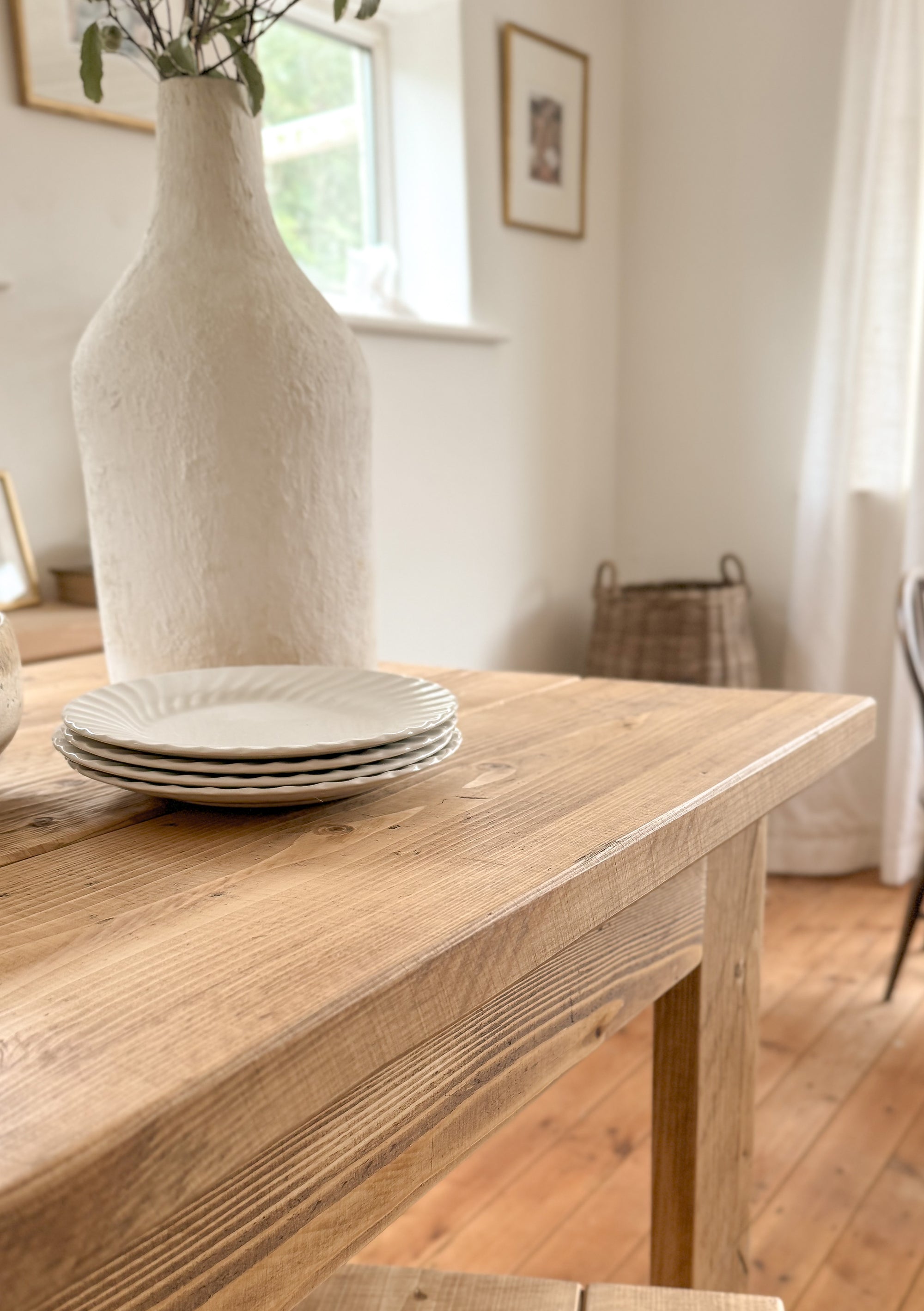bar table with white plates and a vase in a room with a window and curtains.