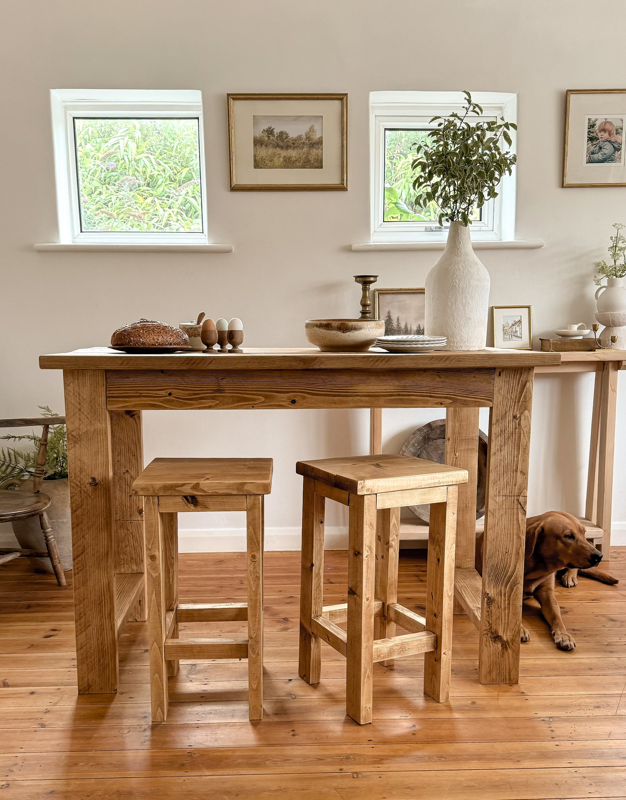 Bar table with stools in a room with windows and decor.