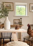 Close up of the Refectory dining table end showing reclaimed wood detail and a chicken sitting in the chair at the end.