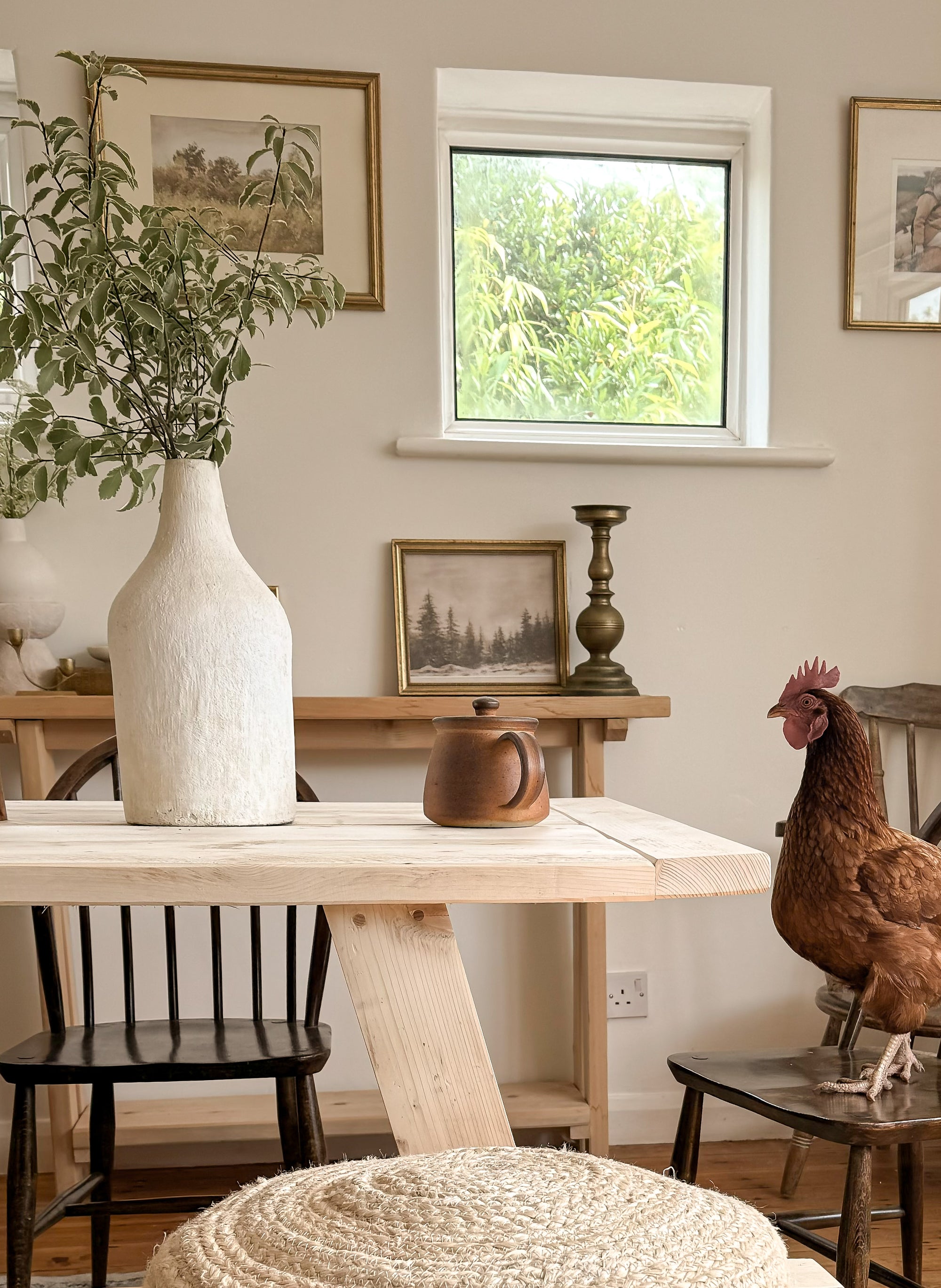 Close up of the Refectory dining table end showing reclaimed wood detail and a chicken sitting in the chair at the end.