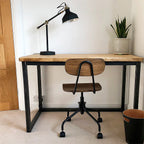 wooden desk with a black lamp and plant and desk chair